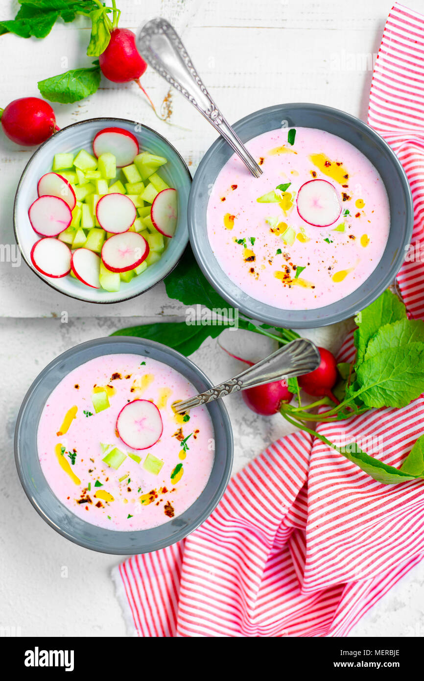 Soupe de radis froide rose avec le concombre et yaourt garnie de piment sec, le poivre, le persil, l'huile d'olive et servi dans des bols crudités Banque D'Images