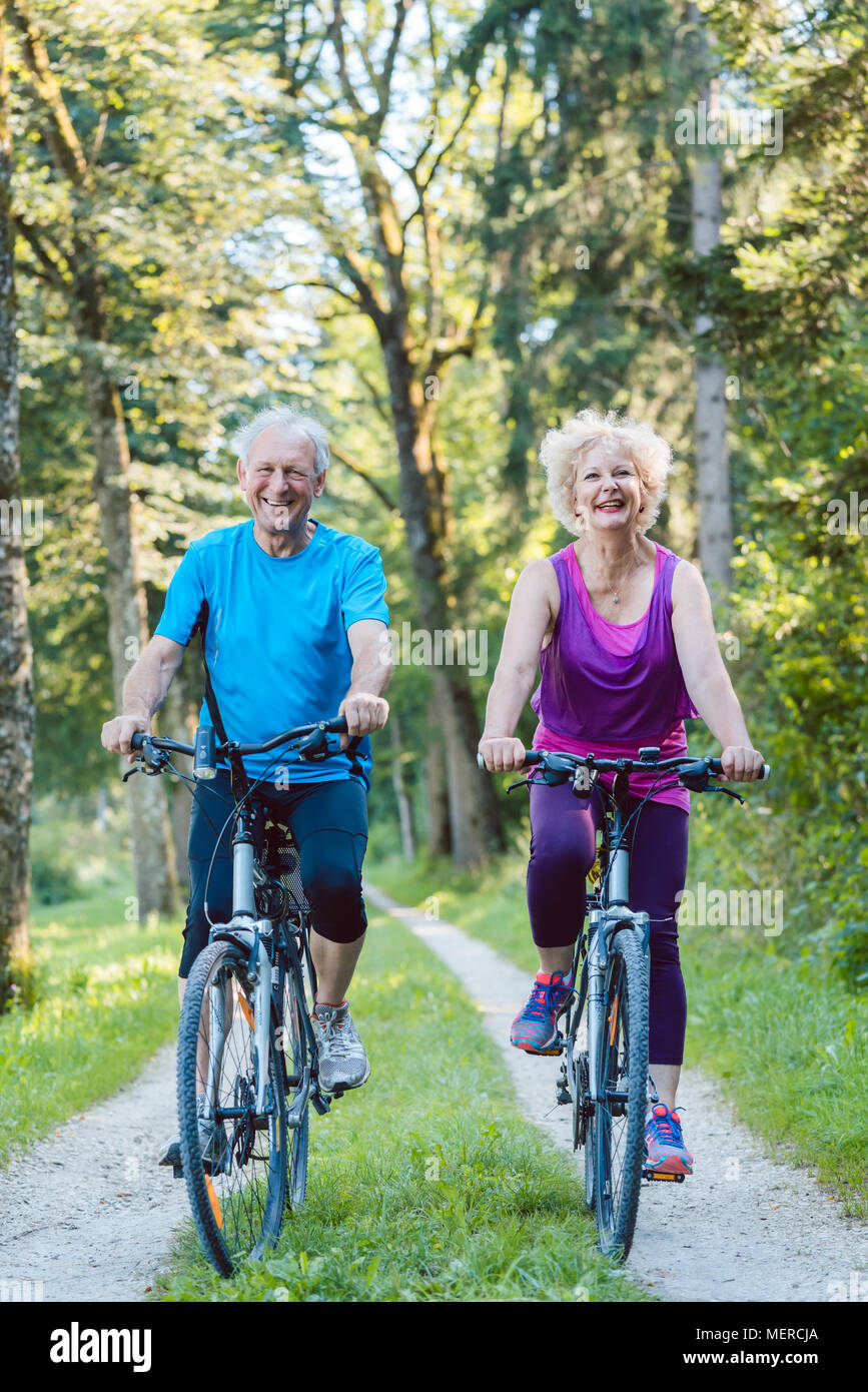 Heureuse et active senior couple riding bicycles outdoors Banque D'Images