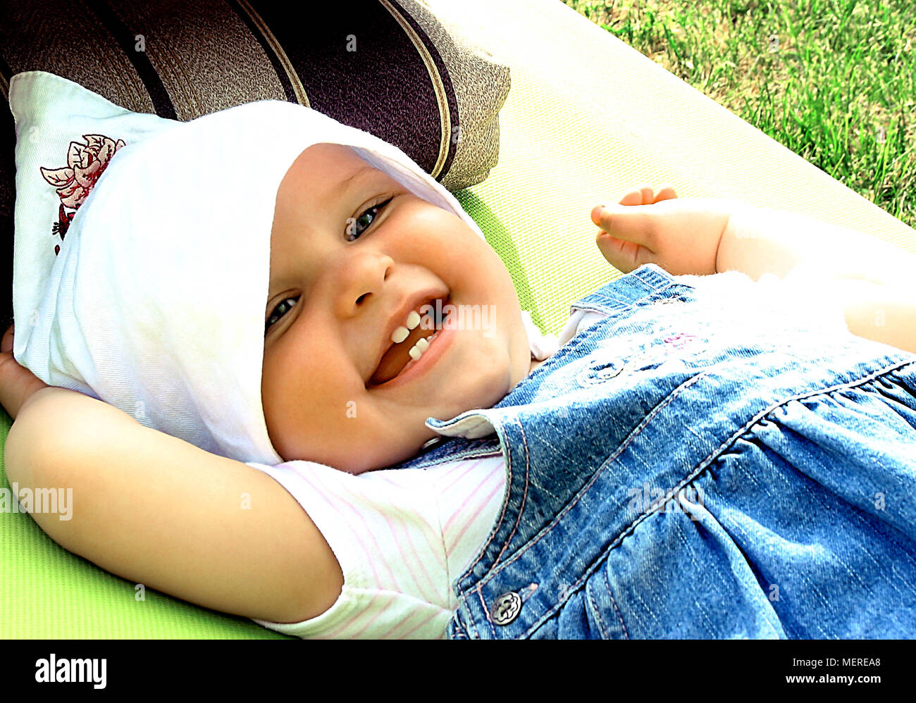 Petite fille dans un foulard, allongé sur la chaise longue dans le jardin. Banque D'Images