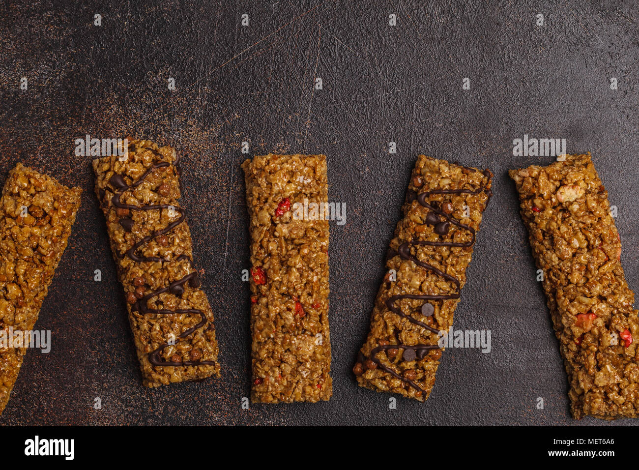 Les barres granola et les ingrédients. Dessert sucré saine collation. Barres de céréales aux noix, chocolat et fruits rouges sur fond sombre. Vue supérieure de la savs copie Banque D'Images