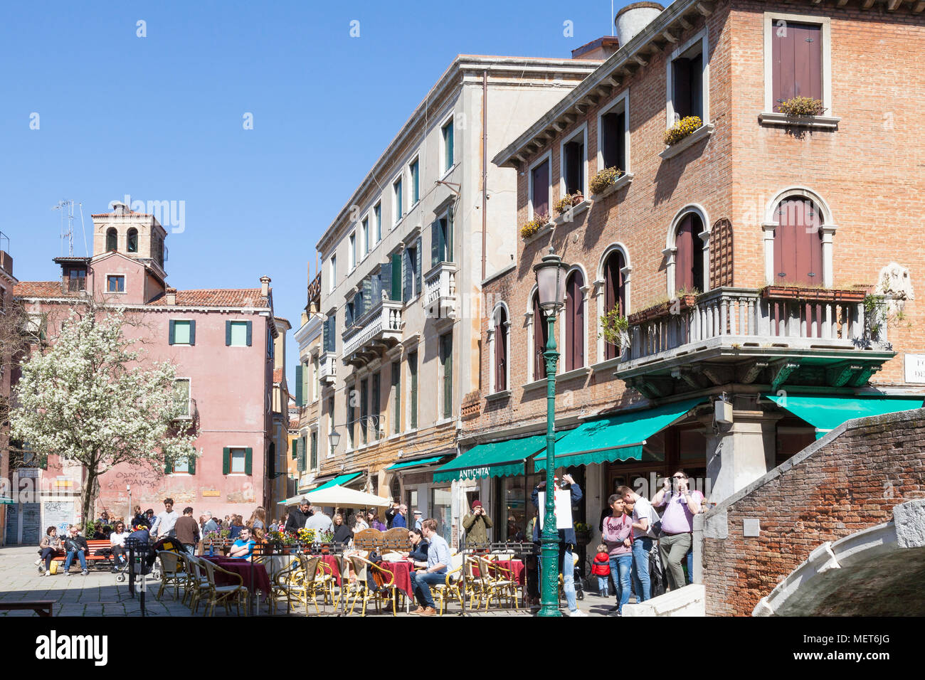 Campo Santa Maria Nova au printemps, Cannaregio, Venise, Vénétie, Italie avec des gens de manger à un restaurant en plein air et un arbre avec des fleurs blanches Banque D'Images