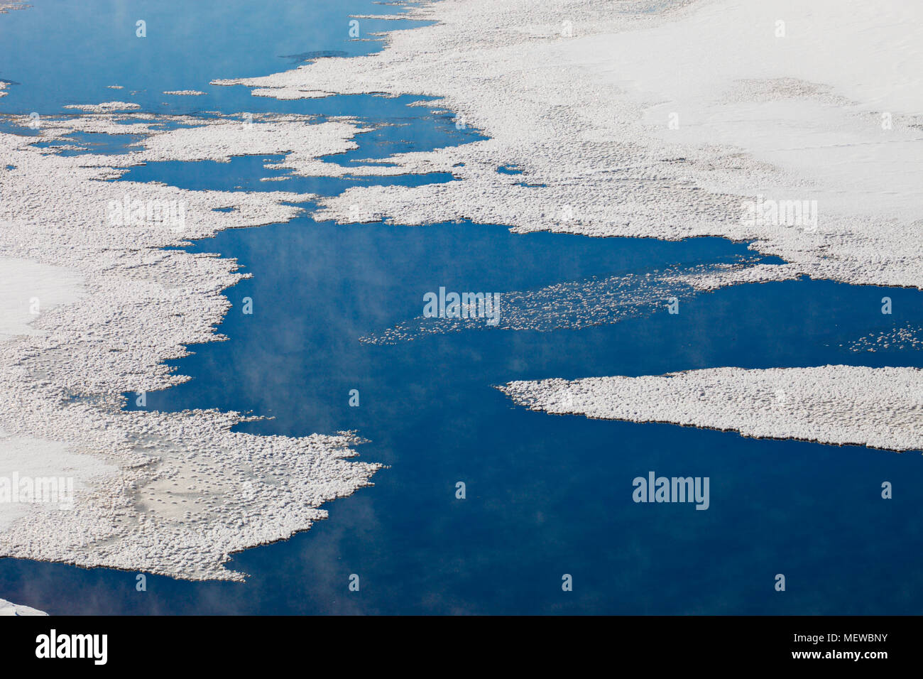 Une fine couche de glace couvre un lac. Traînées de Haze sont surgissant des endroits avec de l'eau libre. Banque D'Images