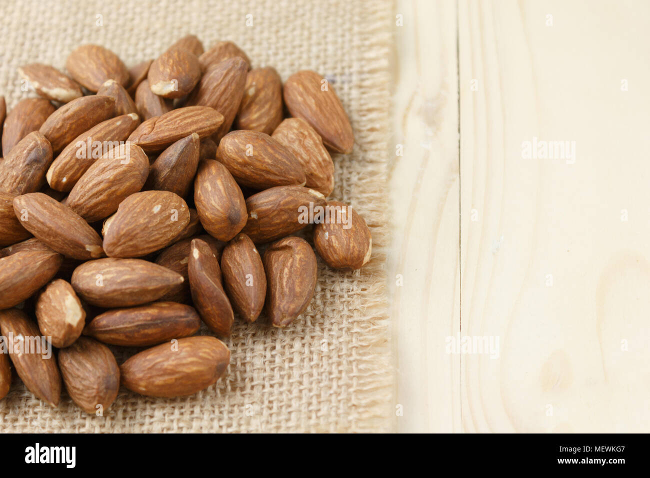 Amandes rôties sur un sac placé sur une table en bois, les amandes background Banque D'Images