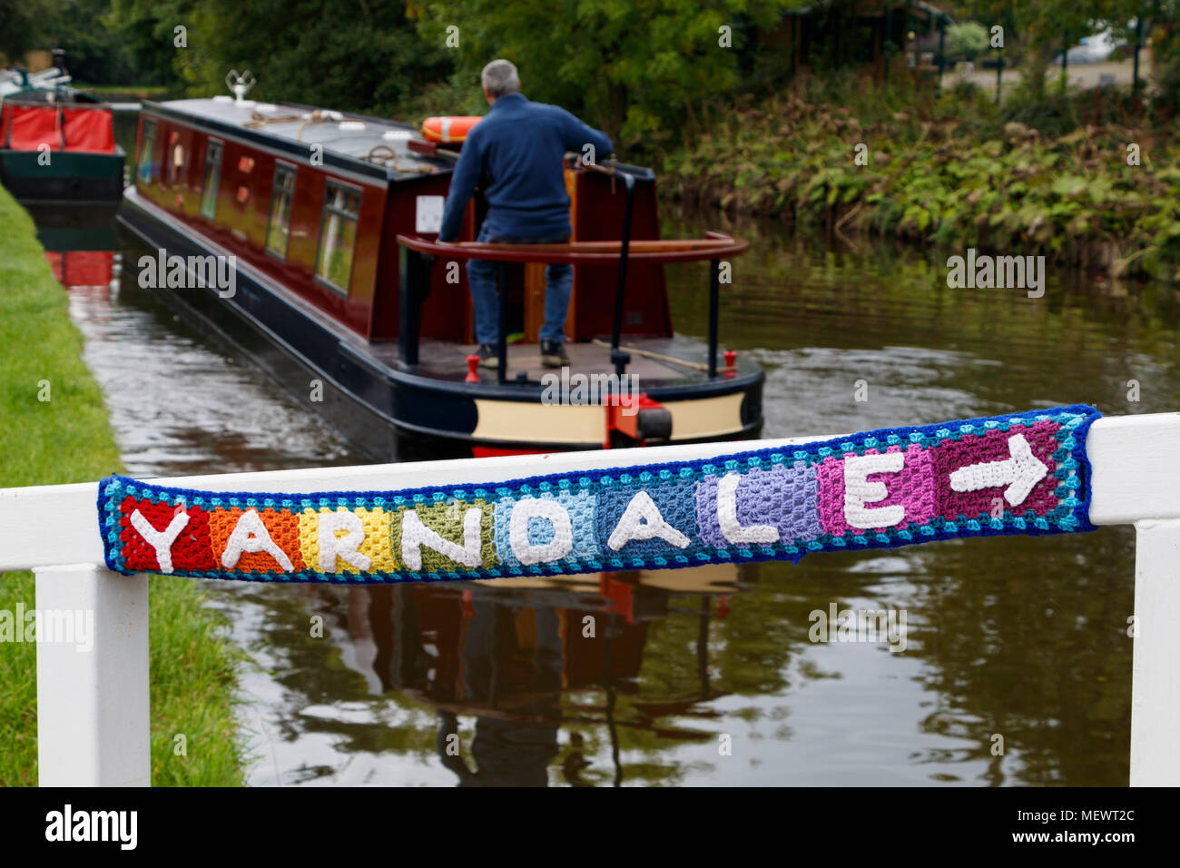 La laine tricotée direction pointeur sur le pont tournant sur le canal de Leeds et Liverpool à Yarndale, Skipton, Yorkshire du Nord, au Royaume-Uni. Banque D'Images
