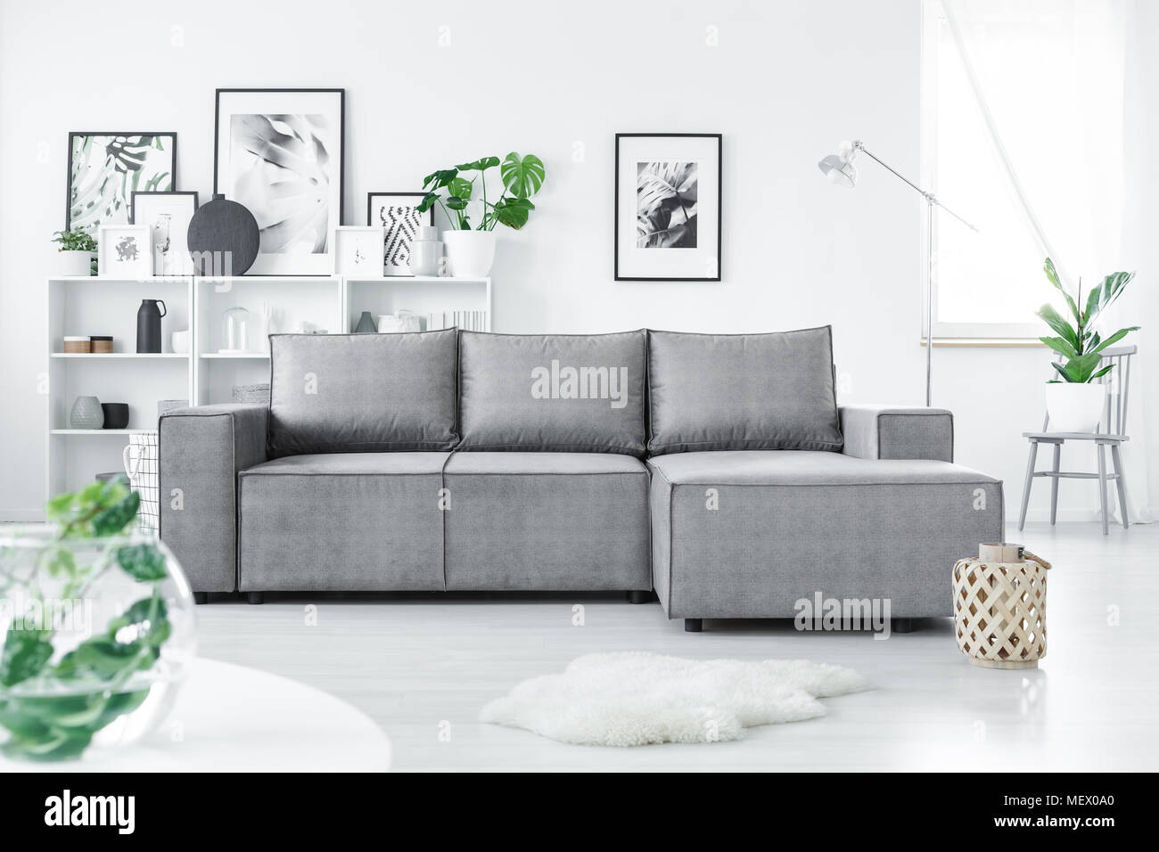 Canapé d'angle gris en blanc permanent salon intérieur avec des plantes vertes et de nombreuses affiches Banque D'Images