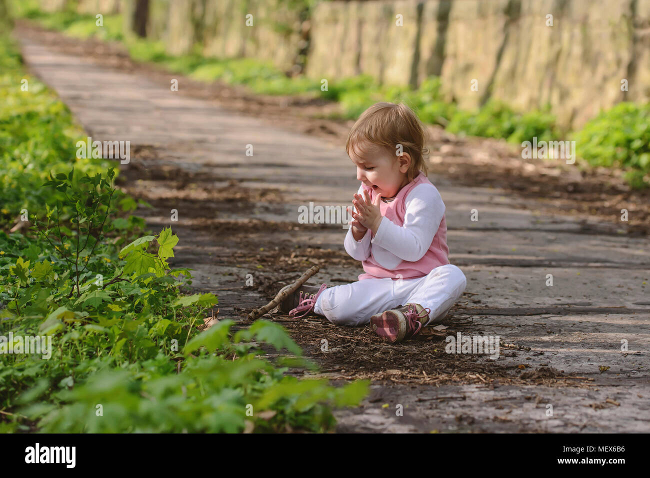 Petit bébé heureux de jouer en étant assis sur la route dans le parc Banque D'Images