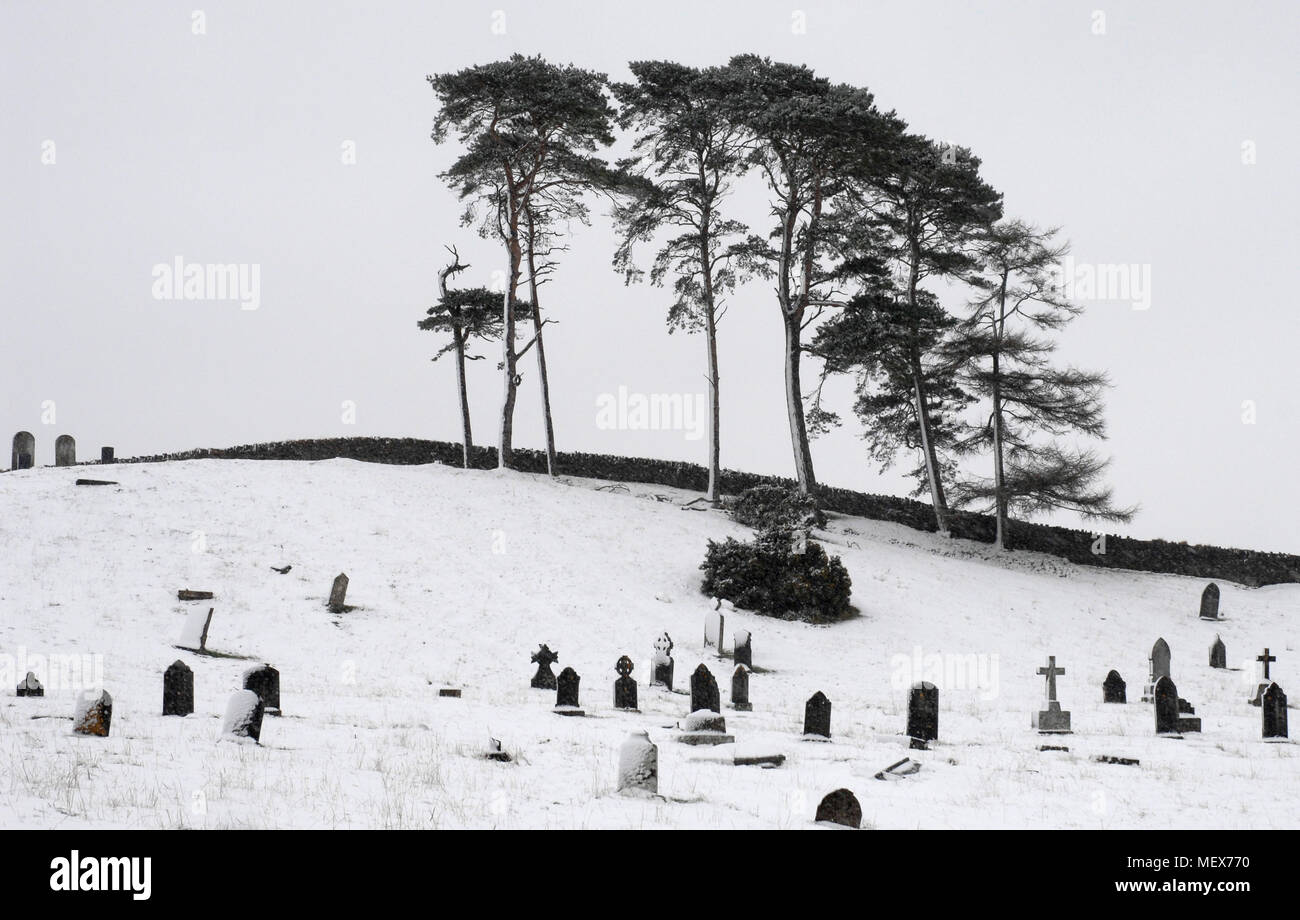 Cimetière couvert de neige avec des pierres tombales et des croix bordée par un muret et quelques arbres Banque D'Images
