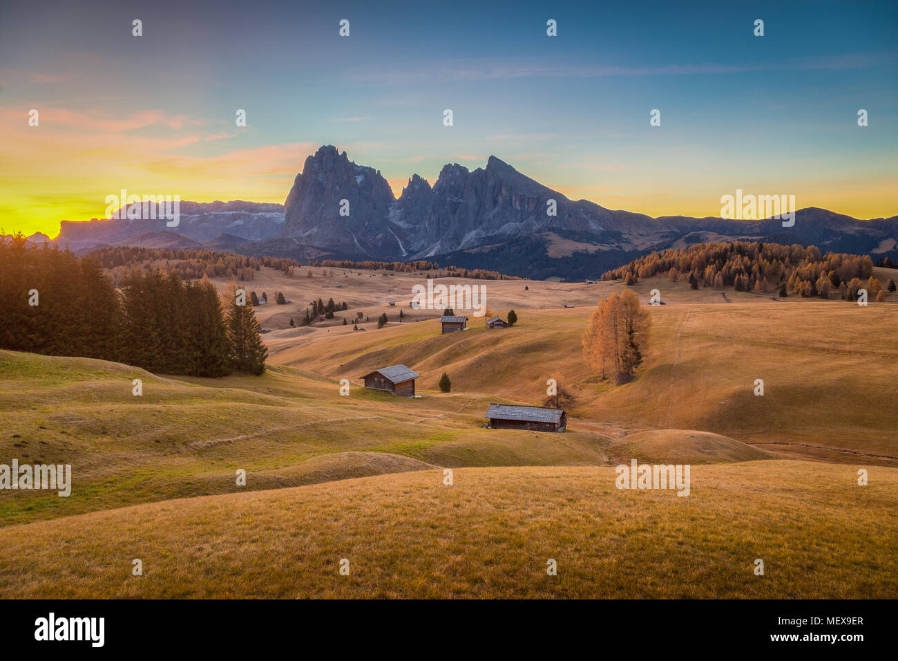 Belle vue sur la montagne chalets traditionnels en bois sur Scenic Alpe di Siusi célèbre Langkofel avec des pics de montagne dans l'arrière-plan au lever du soleil, de l'Italie Banque D'Images