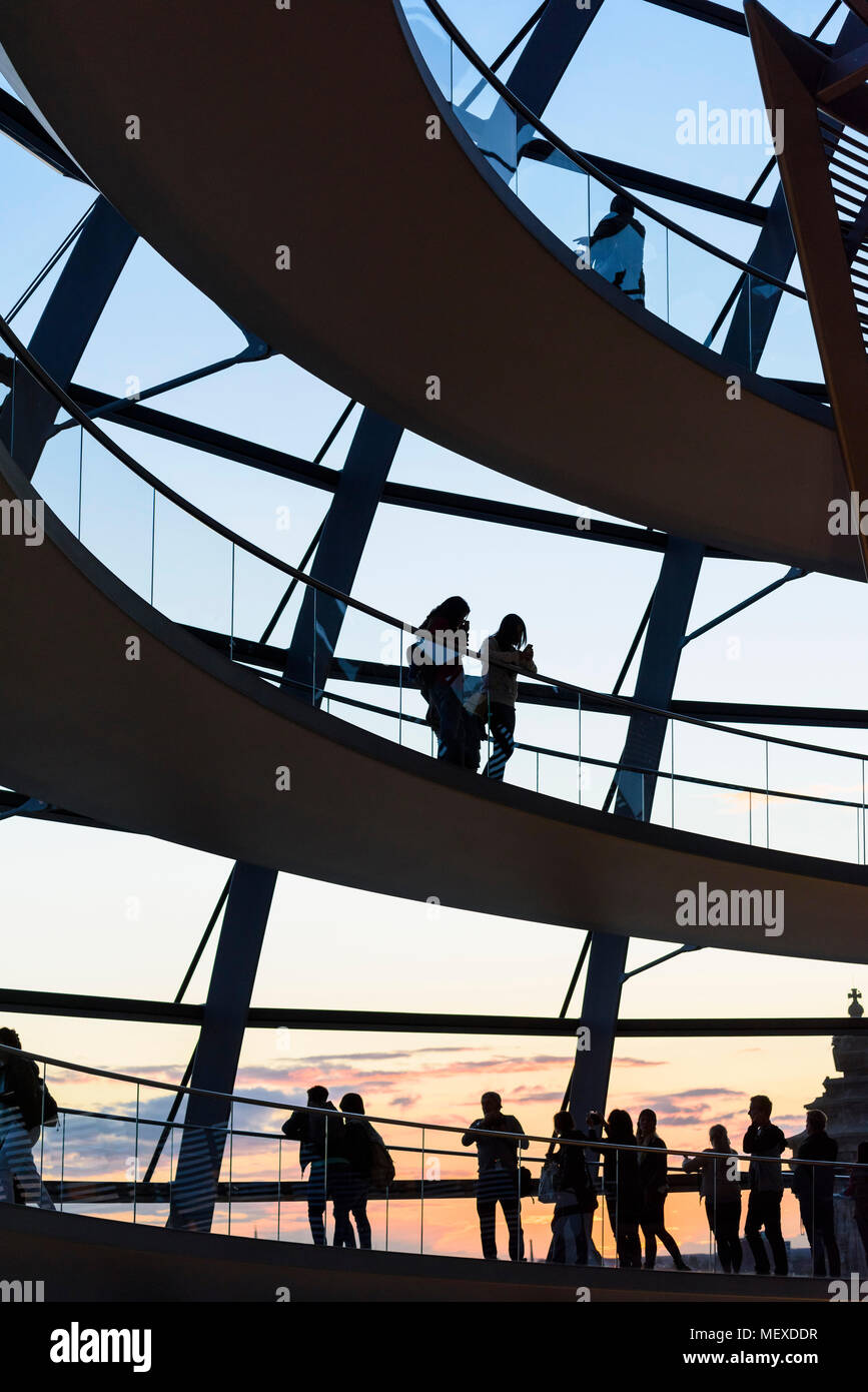 Berlin. L'Allemagne. Les visiteurs de la coupole du Reichstag silhoutted contre le coucher du soleil. Banque D'Images