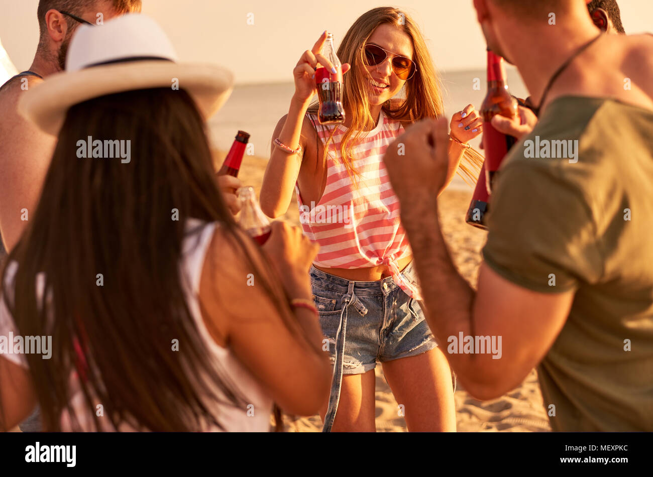 Les jeunes extatique de boire de l'alcool et danser sur la plage Banque D'Images
