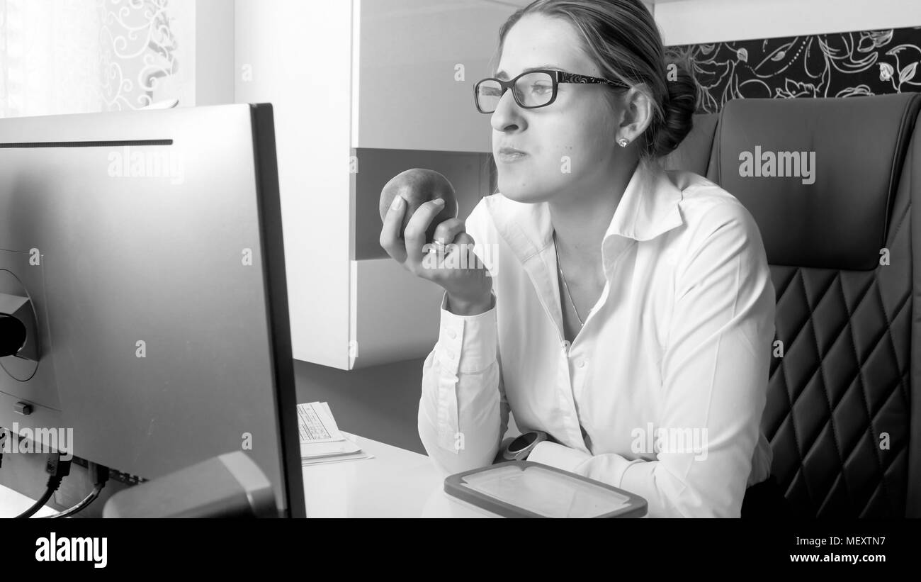 Le noir et blanc portrait of young businesswoman avec apple at office Banque D'Images