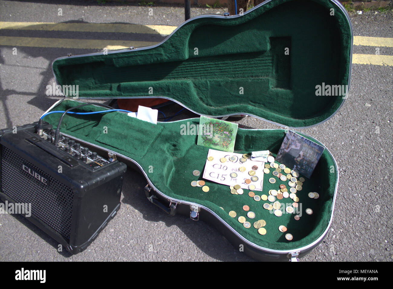 Étui à guitare montrant dernière sortie du cd d'un musicien de rue et de l'argent recueillis auprès des passants, avec un amplificateur sur la route.La monnaie est l'euro Banque D'Images