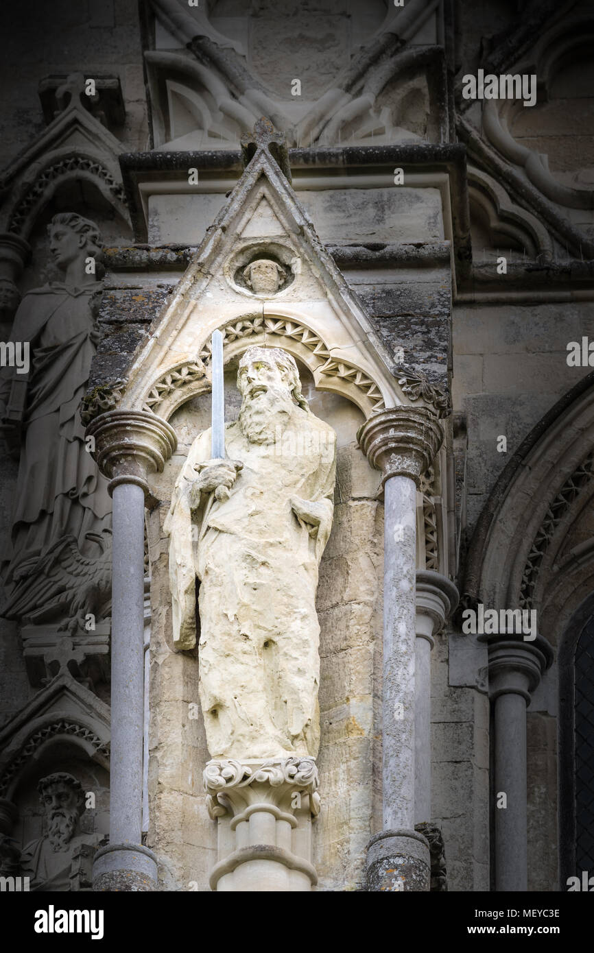 Sculpté patiné statue en pierre de St Paul l'évangéliste à l'extérieur du mur ouest de la cathédrale médiévale de Salisbury, Angleterre. Banque D'Images
