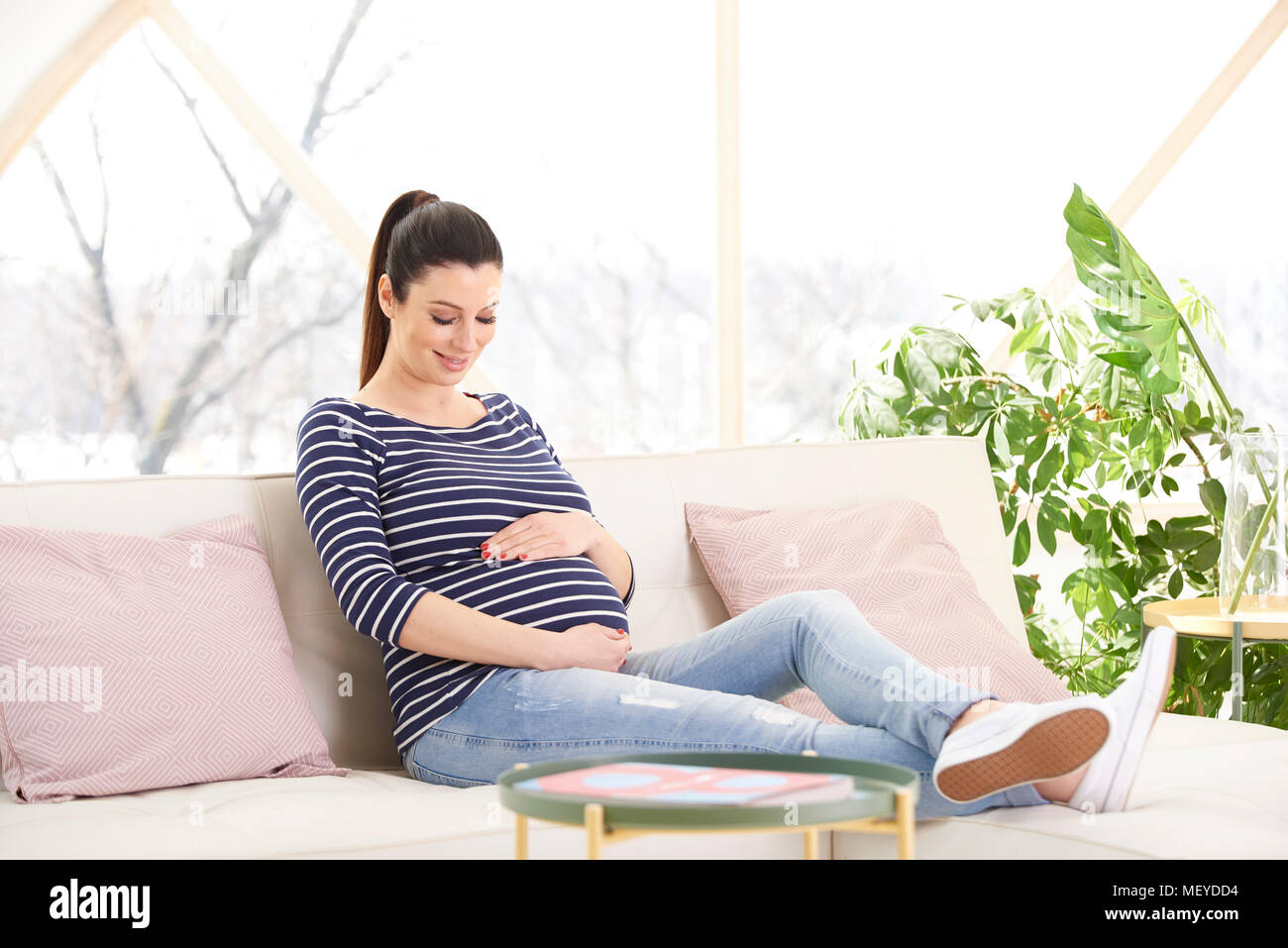 De Toute La Longueur Pregnant Woman Sitting On Sofa Et Toucher Son Bebe Tout En Bosse De Detente A La Maison Photo Stock Alamy