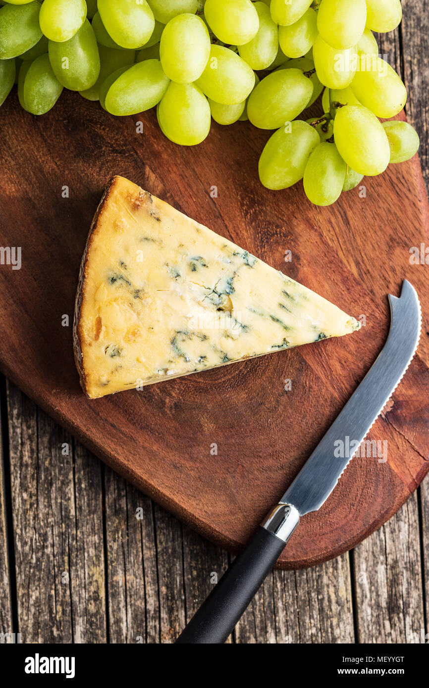 Fromage bleu savoureux avec des raisins sur une planche à découper. Banque D'Images