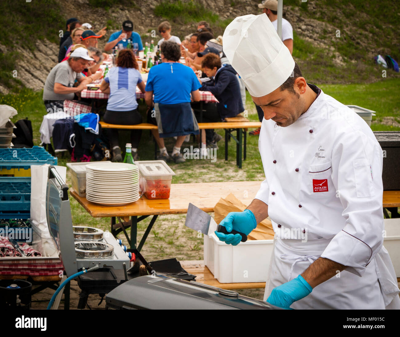 Marathon de randonnée à travers la Toscane. Groupe de randonneurs ayant un pique-nique d'été près de Montalcino, Toscane, Italie. Le chef de l'hôtel Adler Thermai prépare un barbecue Banque D'Images