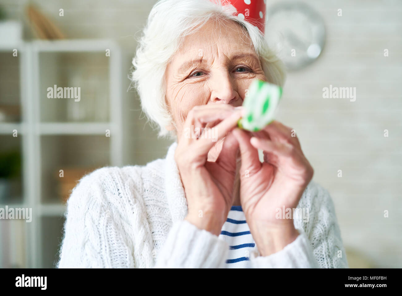 Granny insouciant blowing party horn Banque D'Images