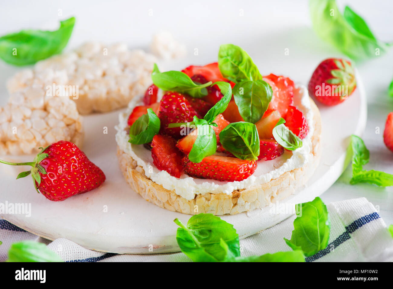 Collation santé avec des fraises fraîches, pain, fromage de chèvre, et les feuilles de basilic. Entrée facile recette. Banque D'Images