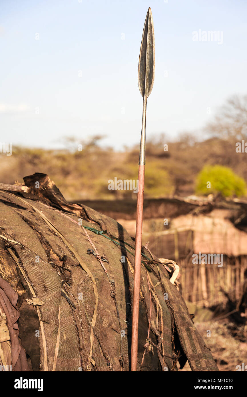Habitation traditionnelle de boue kenyane (manyatta) avec tribal spear placé à l'extérieur. Le village est connu comme un kraal ou boma, la lance est utilisée pour la chasse. Banque D'Images
