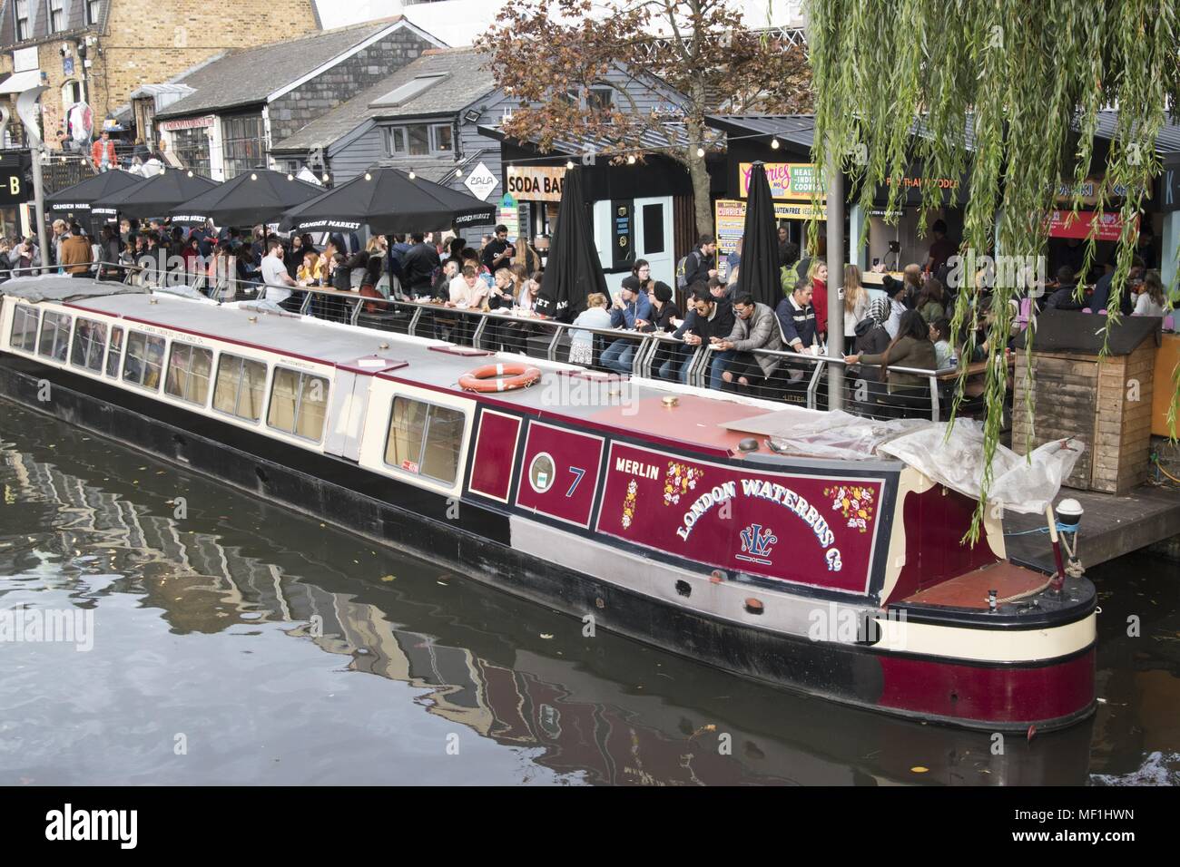 Vue sur le 'Merlin, ' la London Waterbus Company's red et crème, numéro 7, 15-04, barge, ou canal boat, amarré à côté de la foule, dans la région de Camden Camden Lock Market, situé à Camden Town, dans le nord-ouest de Londres, Royaume-Uni, le 28 octobre 2017. () Banque D'Images