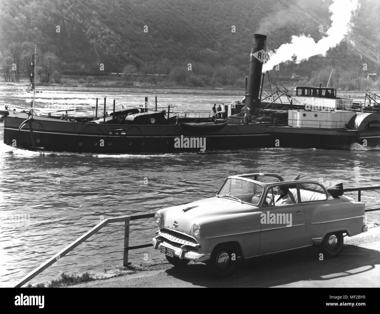 Une Opel Rekord Cabrio sedan en 1955 parcs sur les rives du Rhin. Dans l'arrière-plan, une barge à vapeur passe. L'Opel cabriolet record a été construit de 1953 à 1956. Dans le monde d'utilisation | Banque D'Images