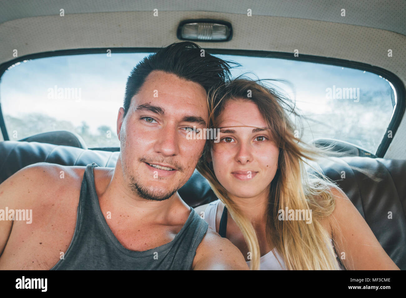 Cuba, jeune couple assis dans une voiture d'époque, en tenant un selfies Banque D'Images