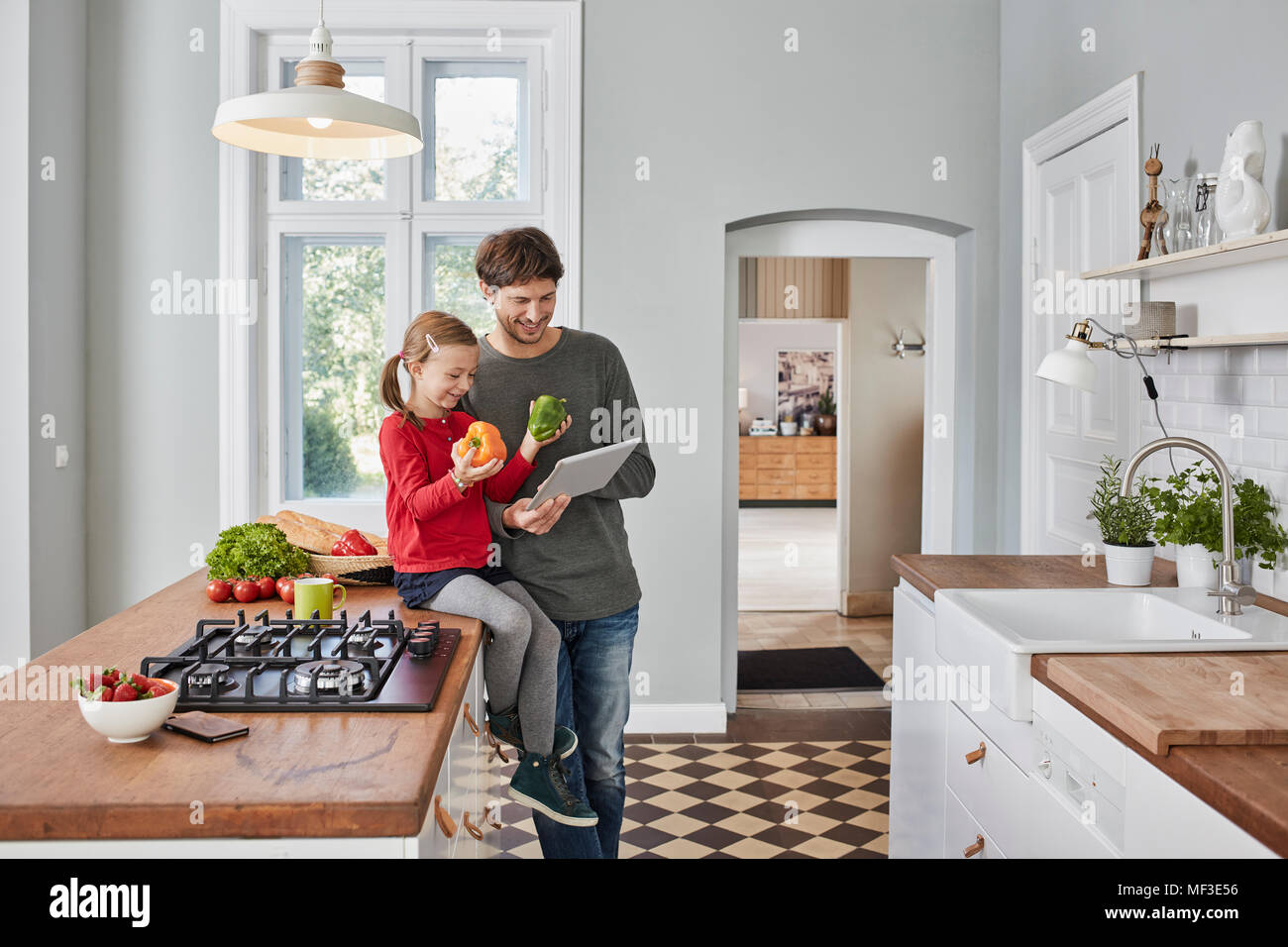 Père et fille souriante aux poivrons et comprimé dans la cuisine Banque D'Images