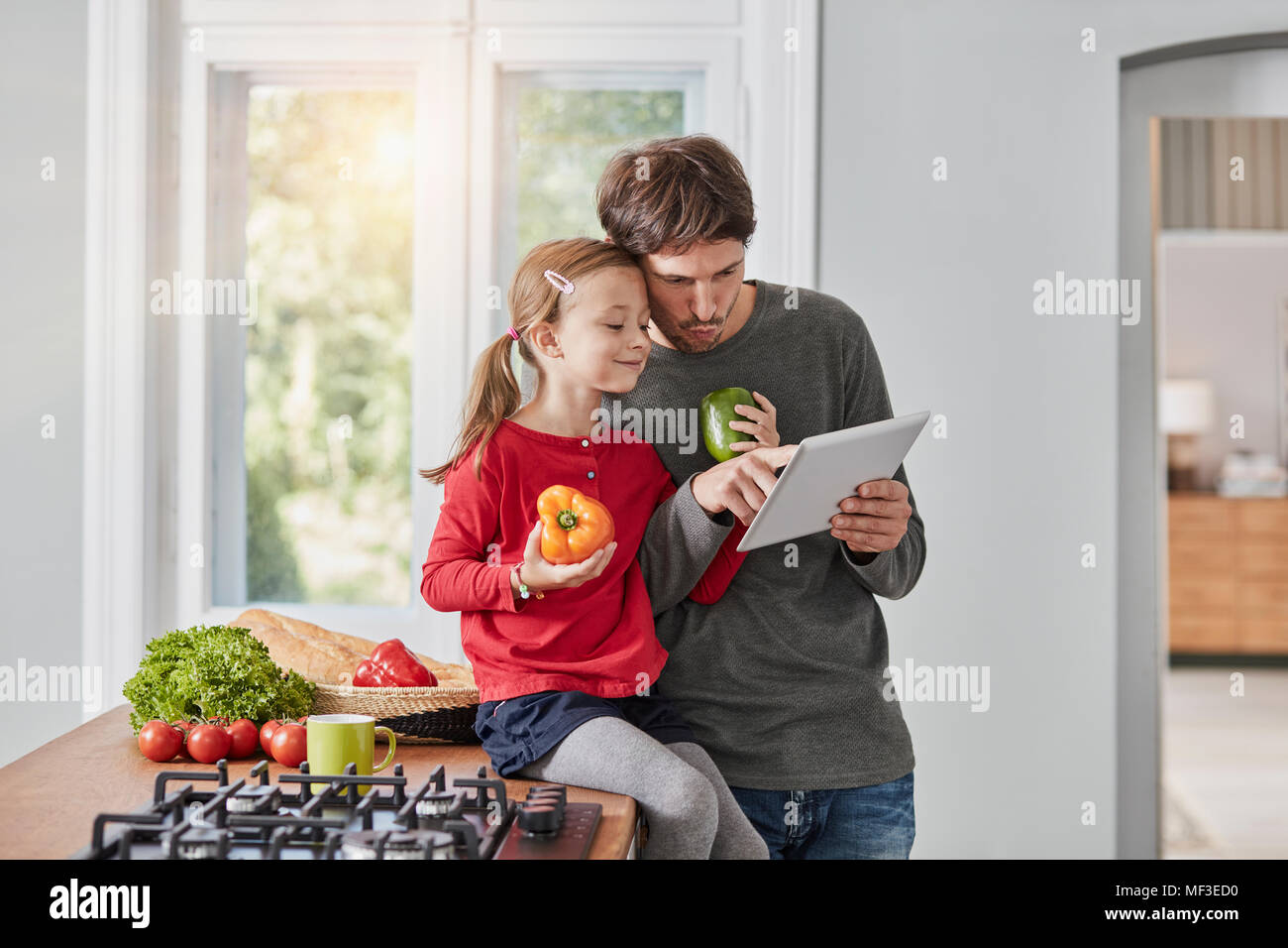 Père et fille aux poivrons et comprimé dans la cuisine Banque D'Images