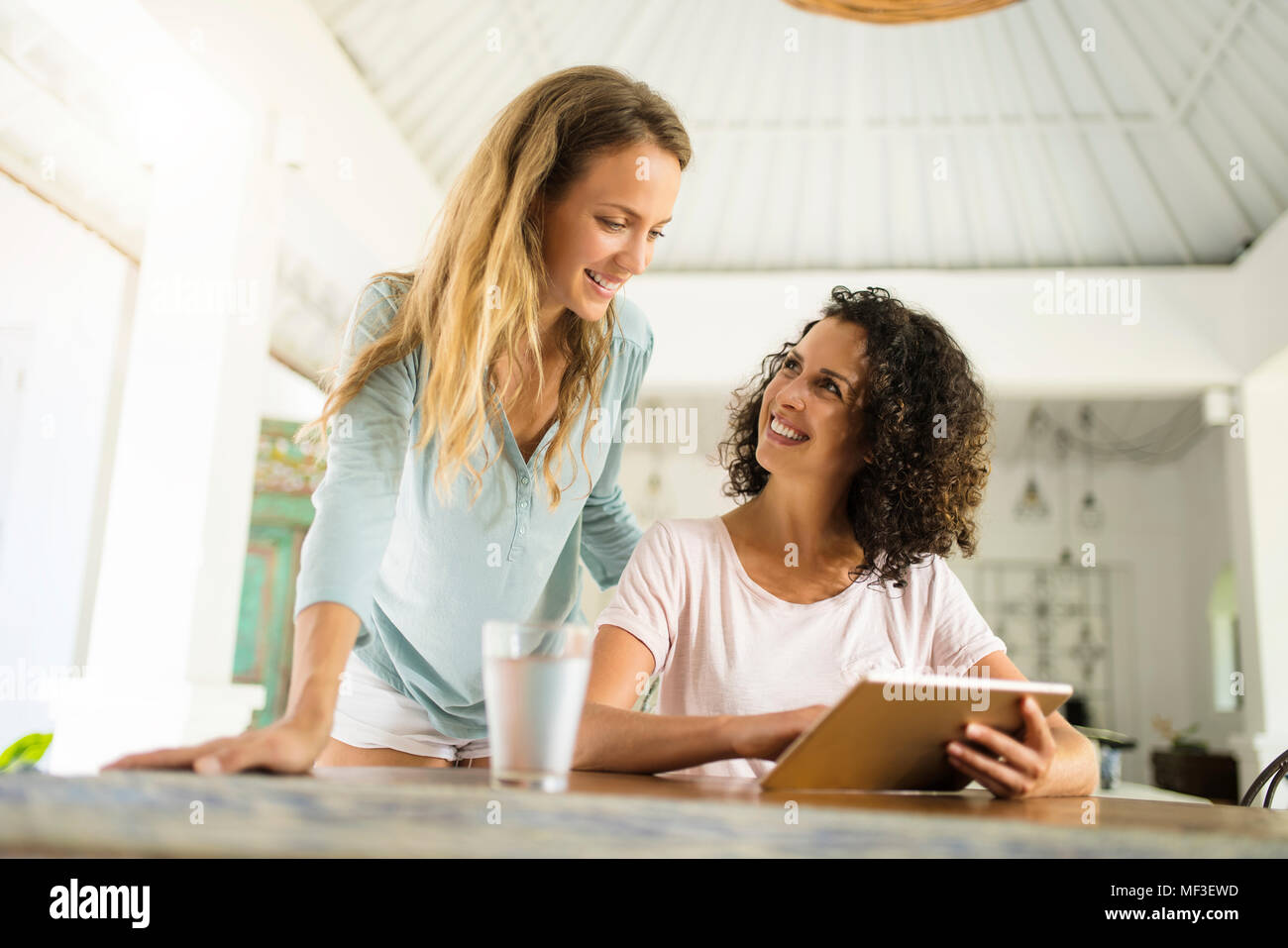 Deux femmes sourire à domicile à l'aide de tablet Banque D'Images