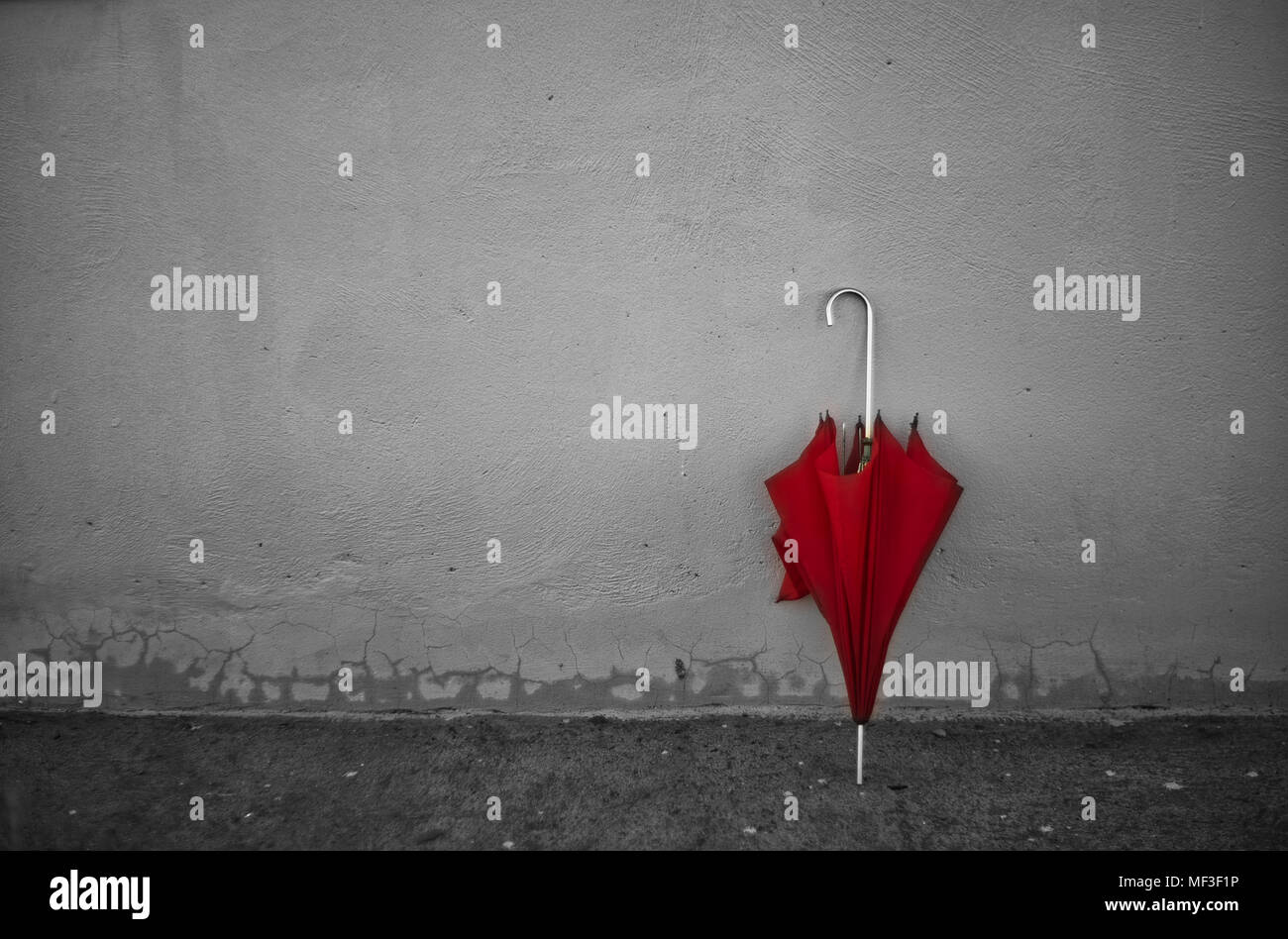 Vintage parapluie rouge appuyée sur un mur gris clair. Banque D'Images