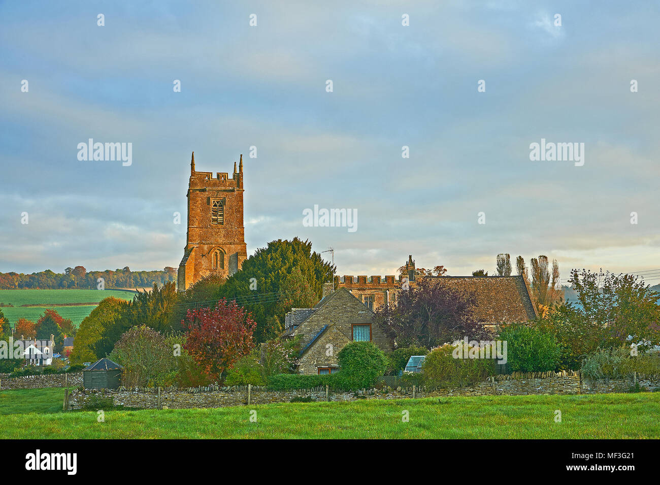 Sud rural scène withSt Warwickshire Peter's Church dans le village de Long Compton avec soleil du matin illumine le clocher de l'église Banque D'Images