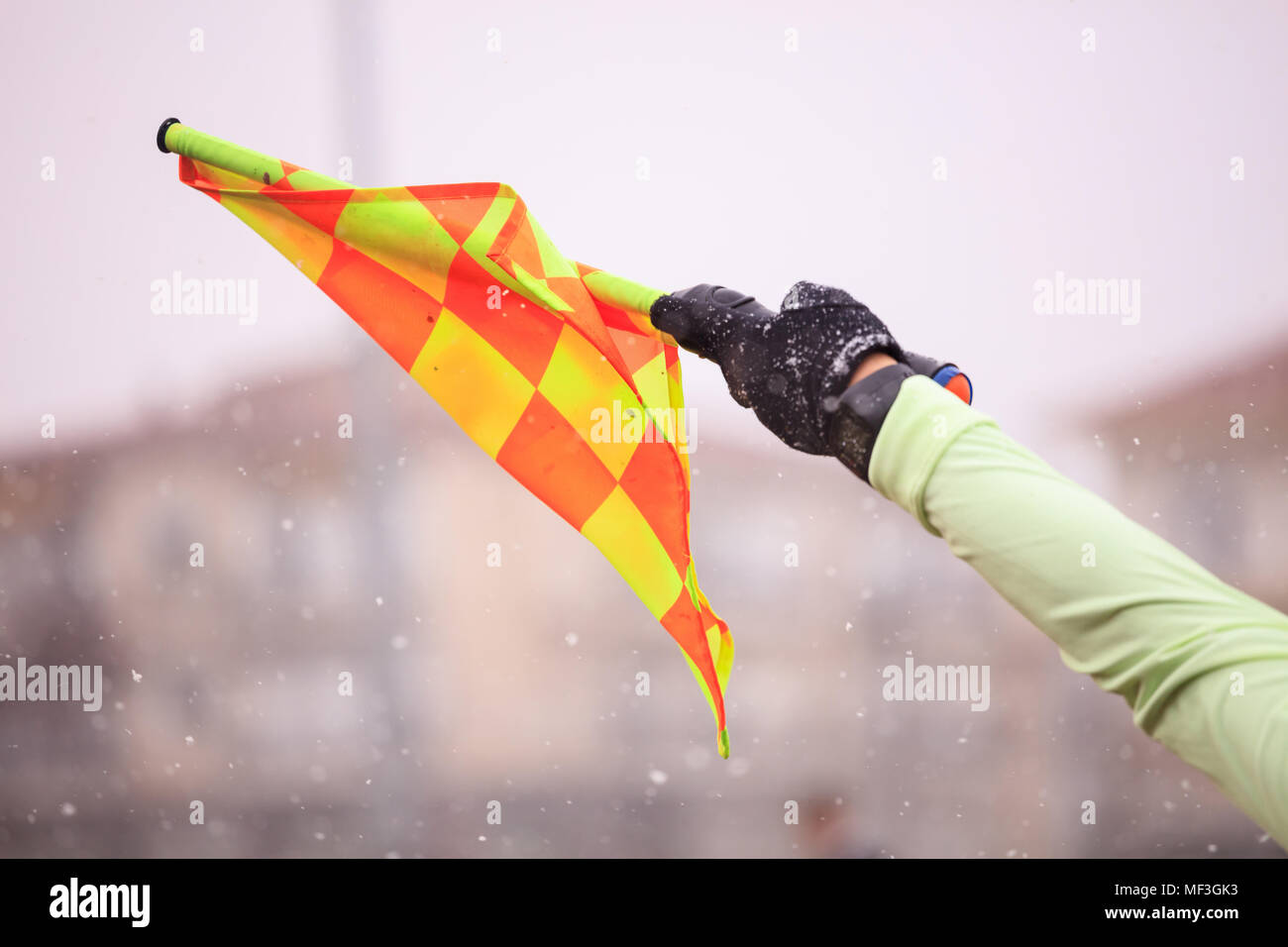 Arbitre de football soccer assistant soulève la drapeau. Arrière-plan de neige floue, vue en gros plan. Banque D'Images
