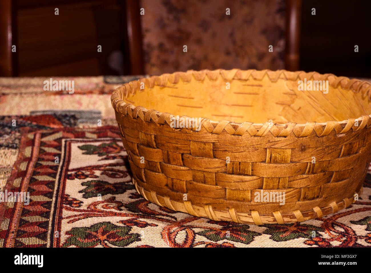 Petit panier en écorce de bouleau télévision traditionnelle pour des produits ('lukoshko') se trouve sur un tapis de table fait maison de couleur tissés Banque D'Images