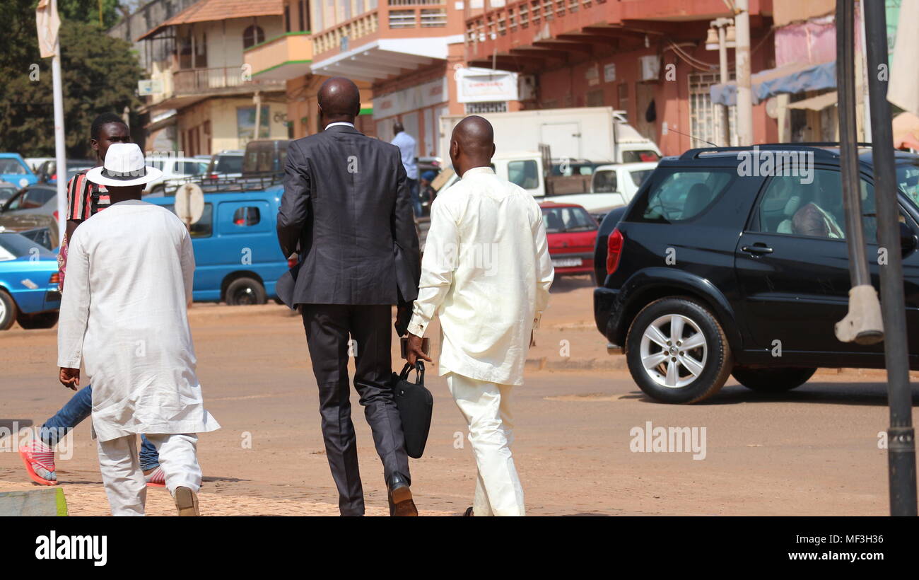 Trois hommes d'affaires d'Afrique de l'Ouest marchant dans la rue avec le dos à la caméra à Bissau, en Guinée-Bissau. Banque D'Images