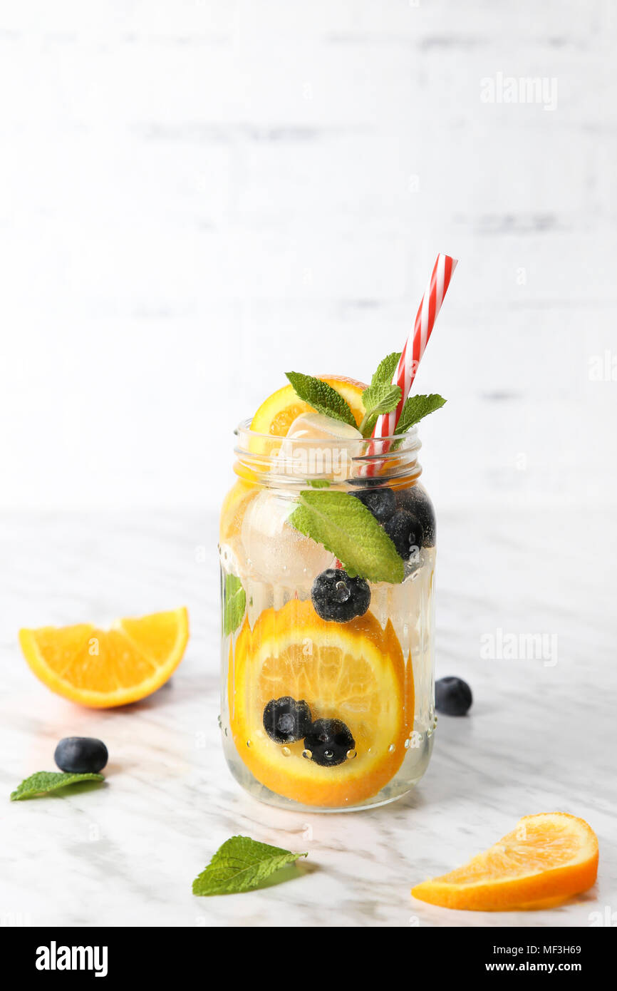 Verre de l'eau infusée avec orange, de bleuets et de menthe sur la glace Banque D'Images