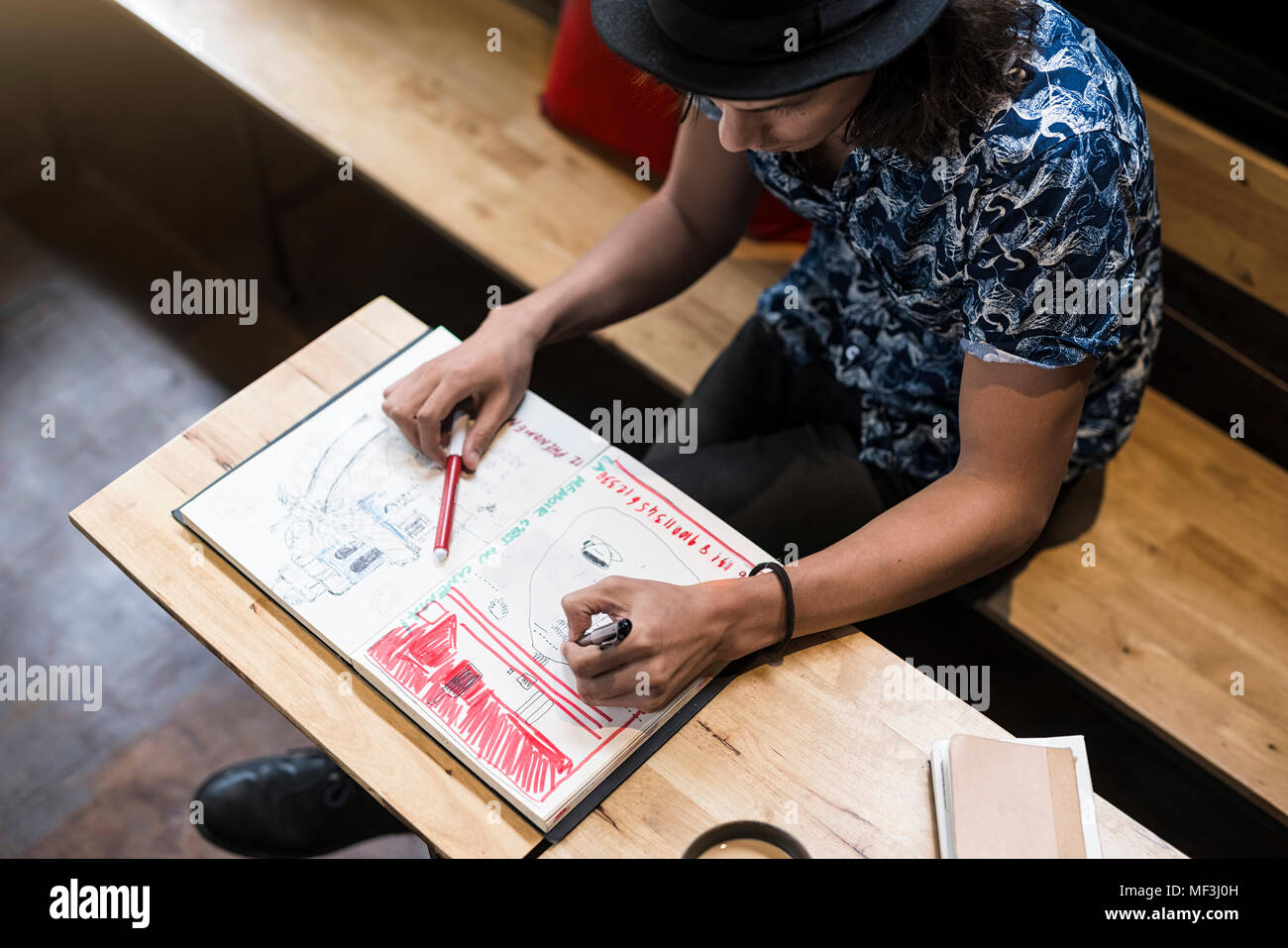 Artiste assis dans un café, dans son carnet de dessin Banque D'Images