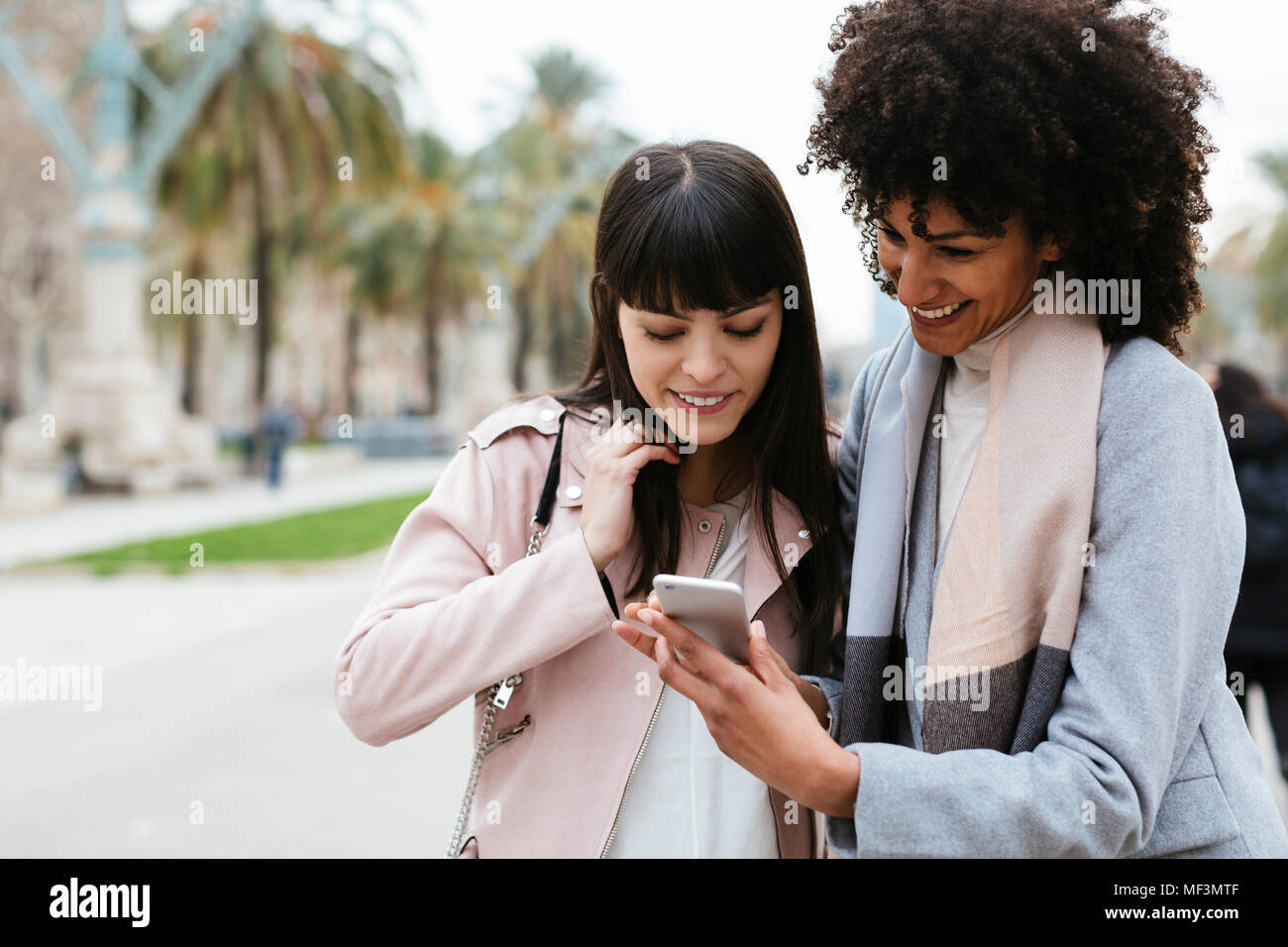 Espagne, Barcelone, deux femmes heureux à la sur téléphone cellulaire sur la promenade Banque D'Images