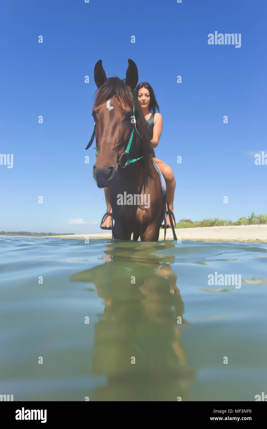 L'INDONÉSIE, Bali, femme assise sur le cheval, dans l'eau Banque D'Images
