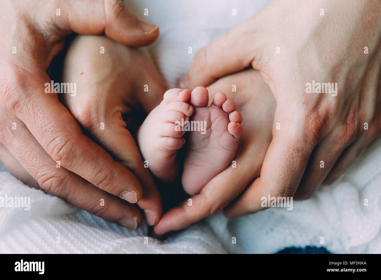 Père et mère's hands holding baby's feet Banque D'Images