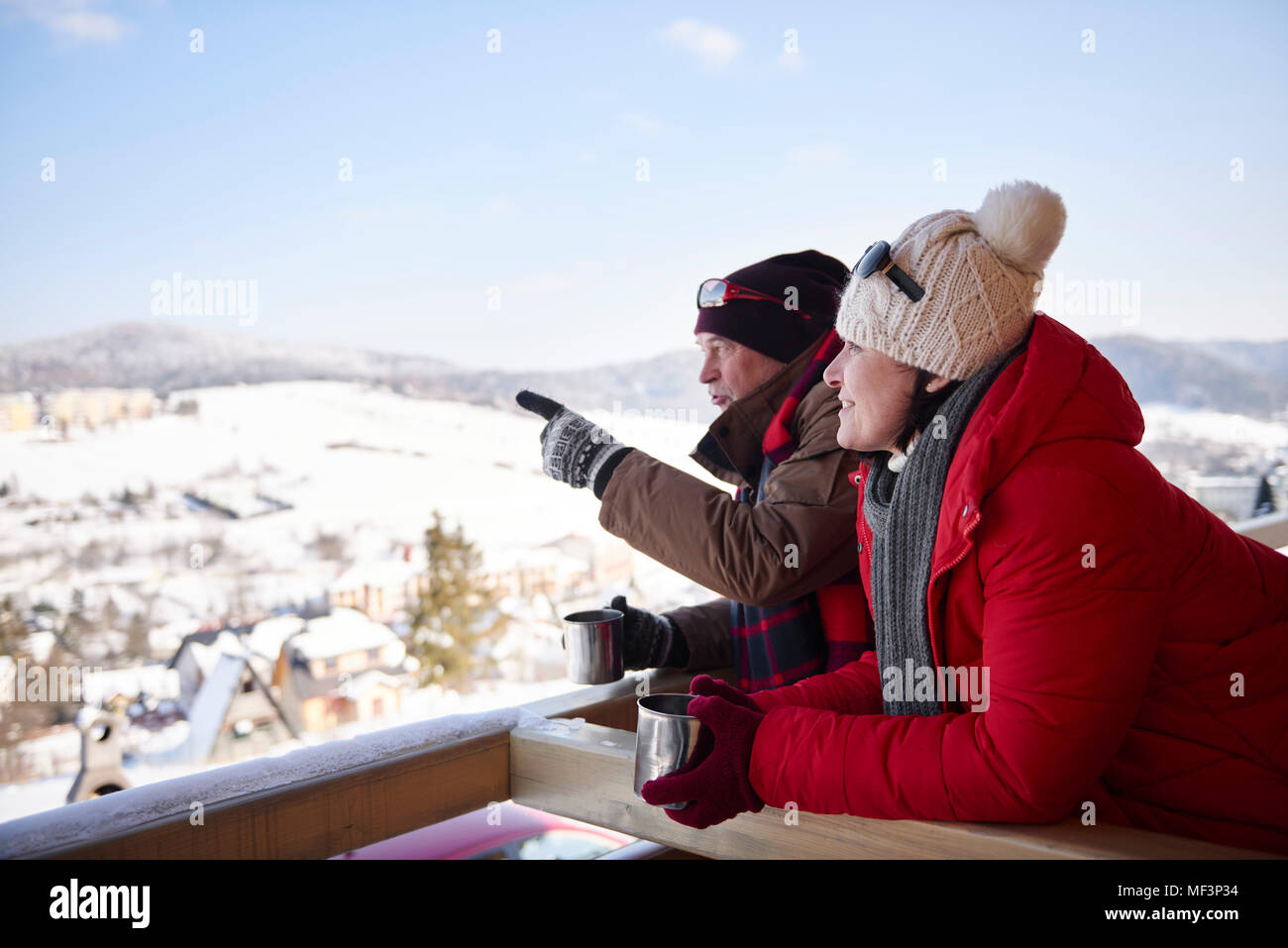 D'âge mûr avec des boissons chaudes à l'extérieur parle au paysage d'hiver Banque D'Images