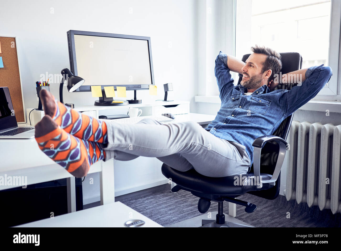 Ambiance man sitting at desk in office looking at computer screen Banque D'Images