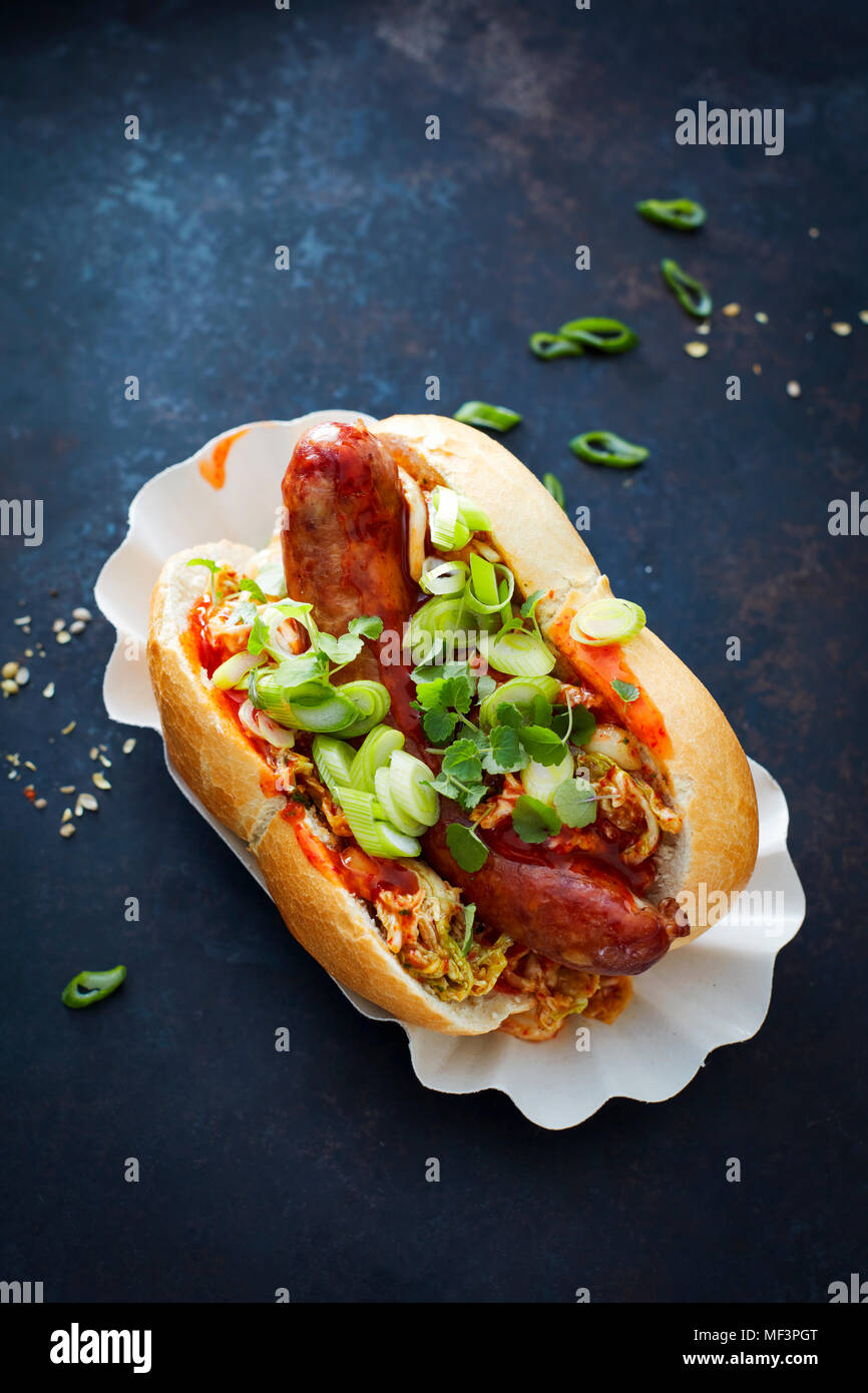 Asian hot-dog, saucisses épicées, chou chinois, hot chili sauce, oignons de printemps, le cresson, bun Banque D'Images