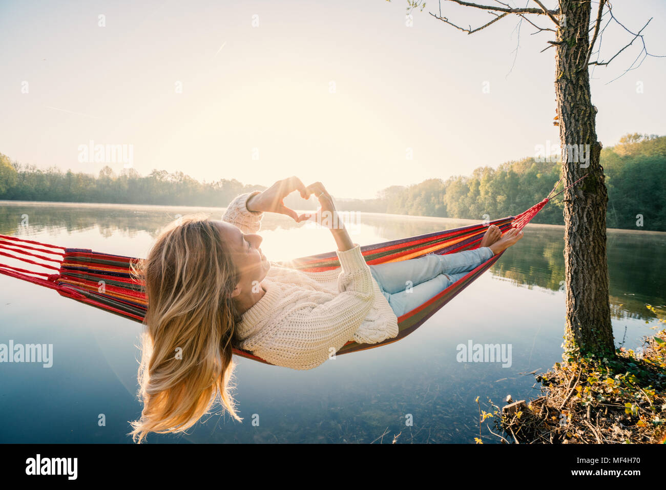 Young woman relaxing on hammock de prendre une forme de coeur sur le magnifique lac image paysage, aimer les gens romance concept. France, Europe Banque D'Images