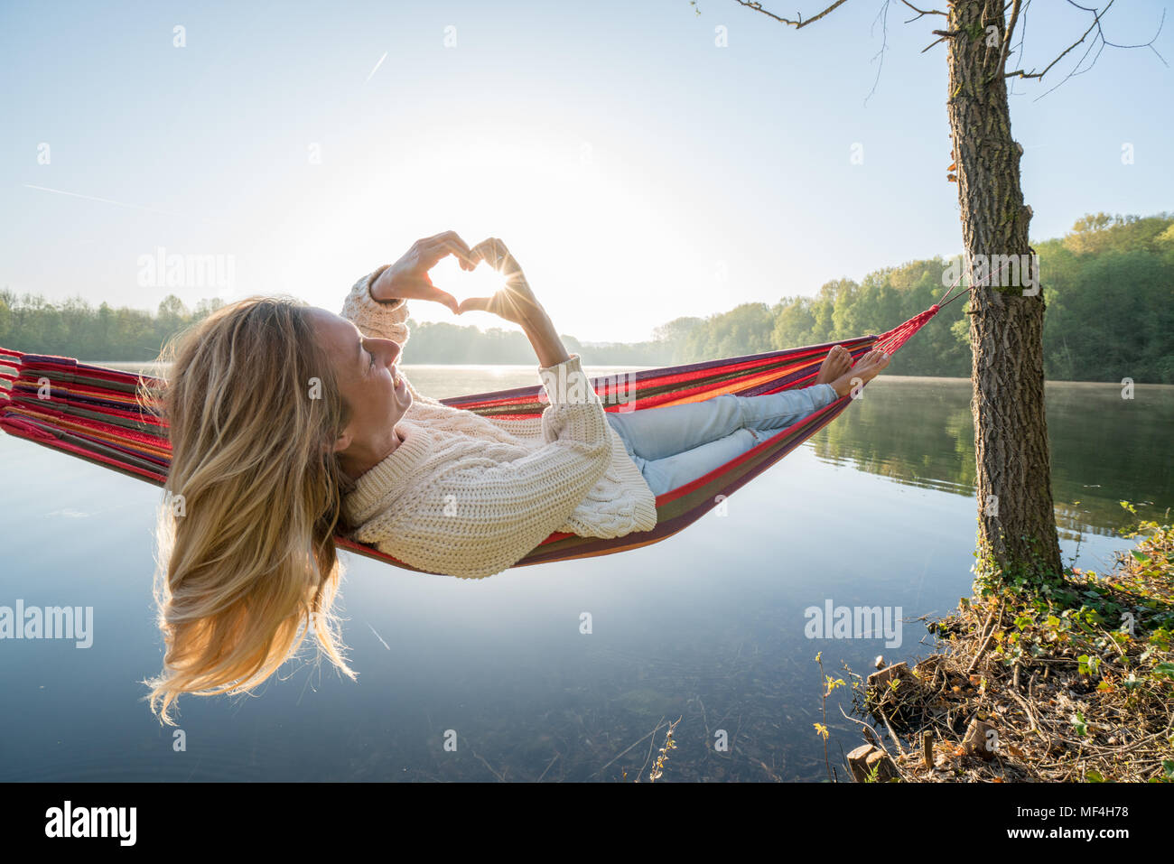 Young woman relaxing on hammock de prendre une forme de coeur sur le magnifique lac image paysage, aimer les gens romance concept. France, Europe Banque D'Images