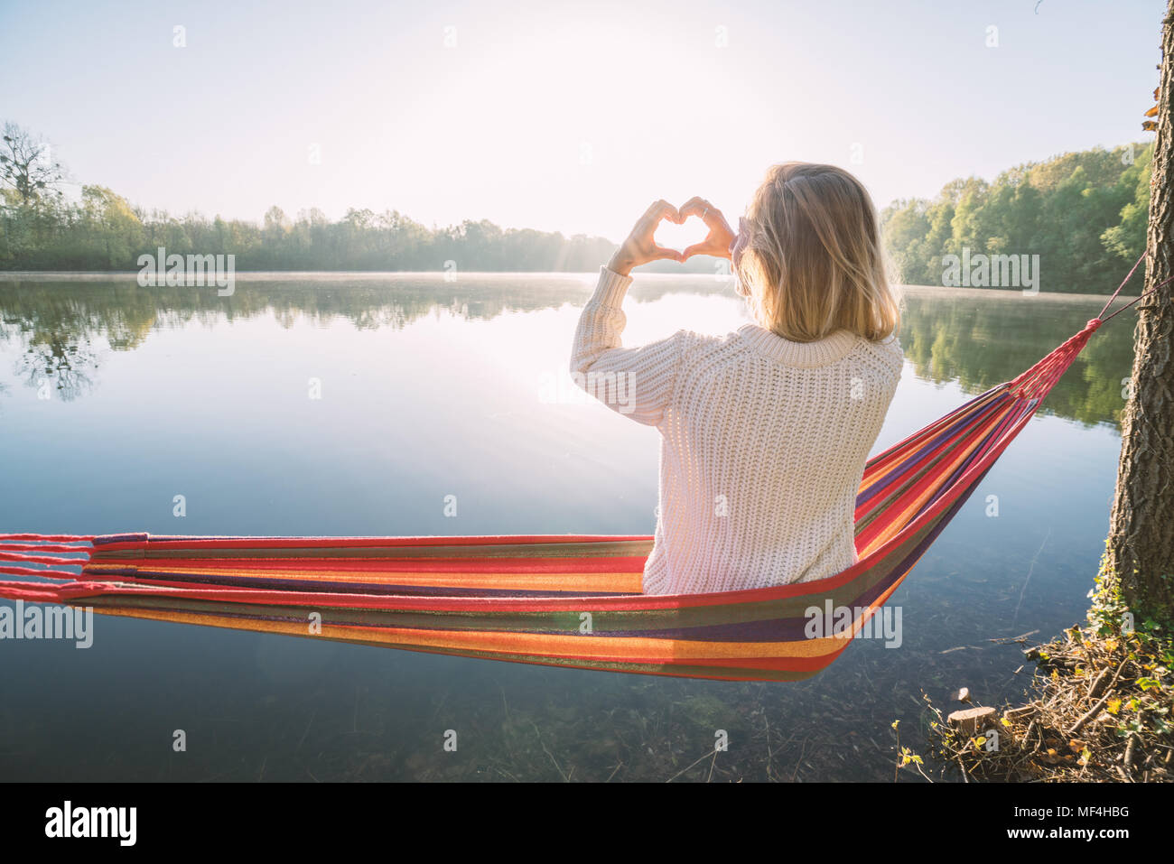 Young woman relaxing on hammock de prendre une forme de coeur sur le magnifique lac image paysage, aimer les gens romance concept. France, Europe Banque D'Images