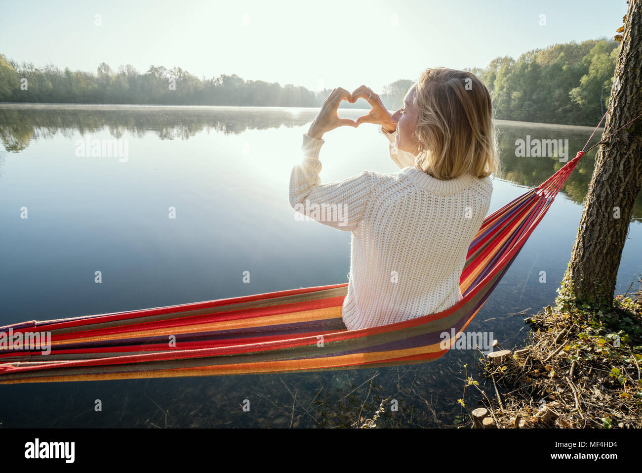 Young woman relaxing on hammock de prendre une forme de coeur sur le magnifique lac image paysage, aimer les gens romance concept. France, Europe Banque D'Images
