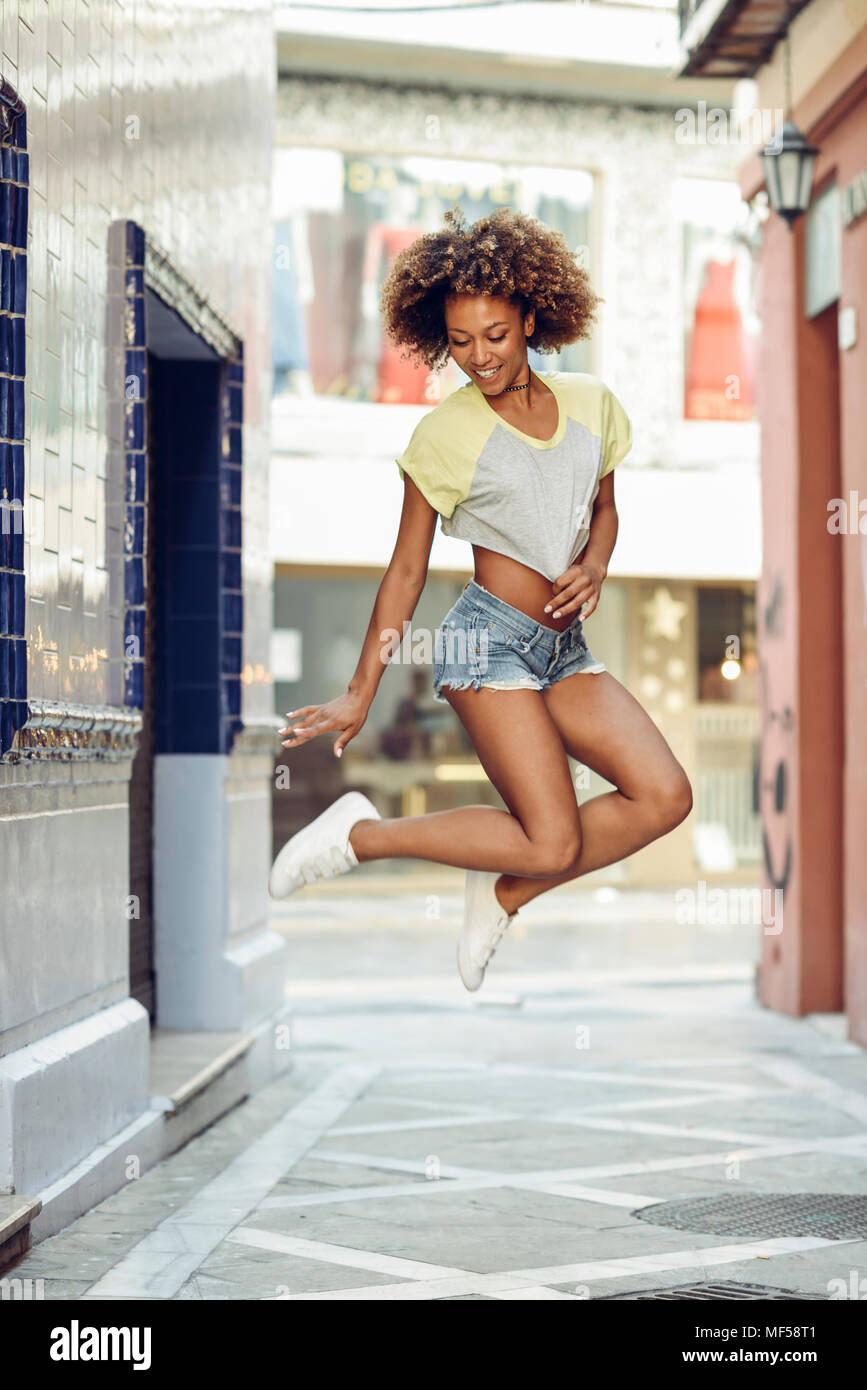 Espagne, Andalousie, Malaga. Happy black woman, afro hairstyle jumping in urban  street portant des vêtements décontractés. Vie de la jeunesse urbaine Photo  Stock - Alamy