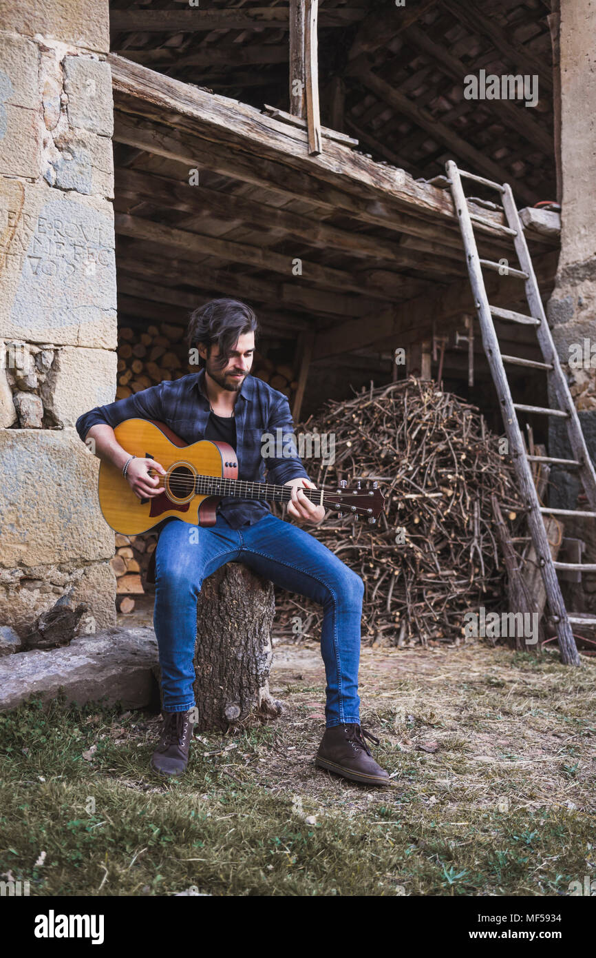 Young man playing guitar dans une ferme Banque D'Images