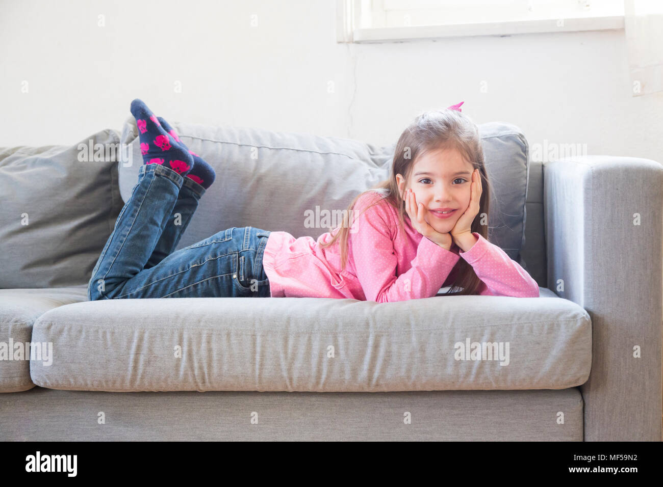 Portrait of smiling little girl couché sur la table Banque D'Images