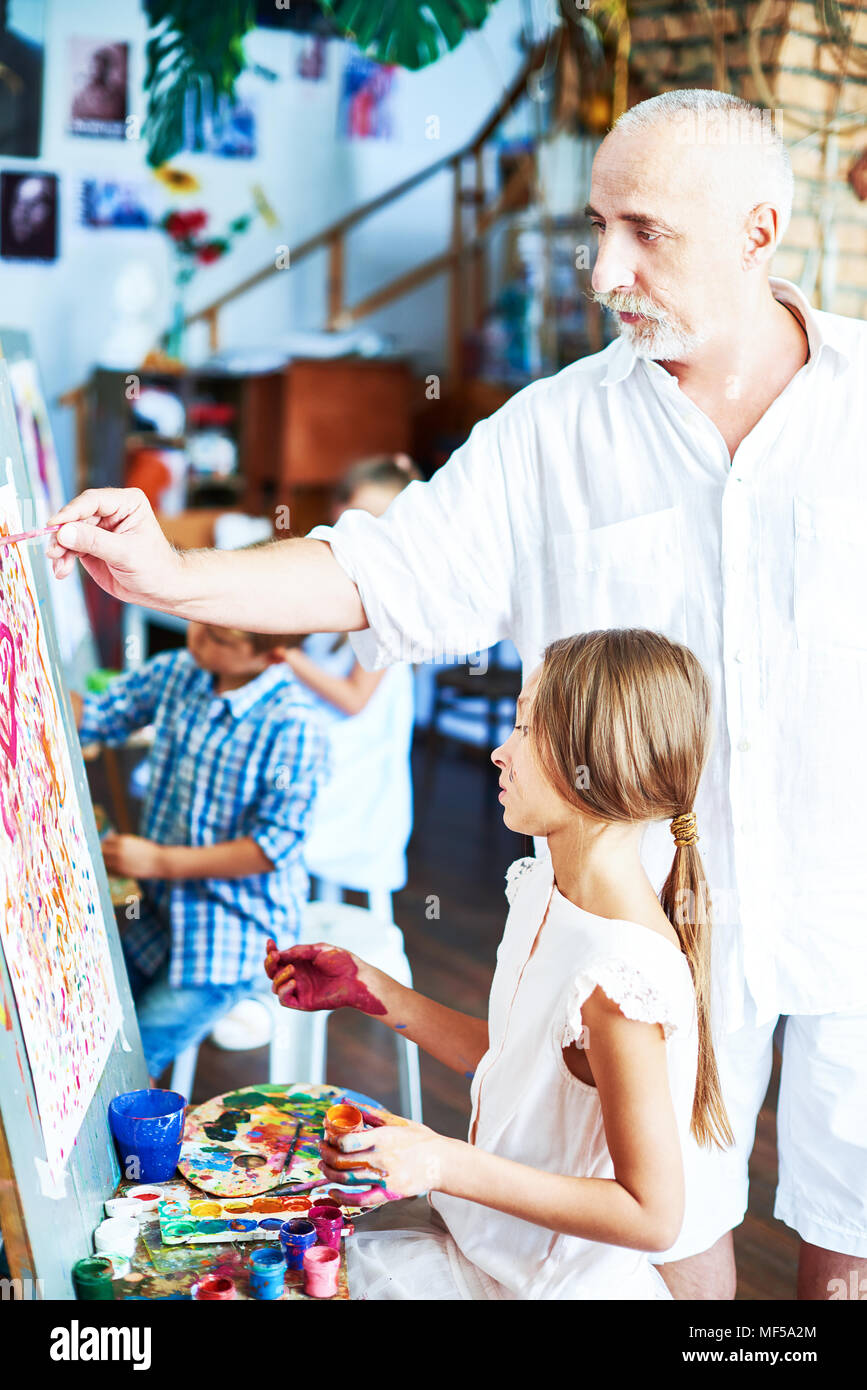 Senior Art Teacher Helping Girl Banque D'Images